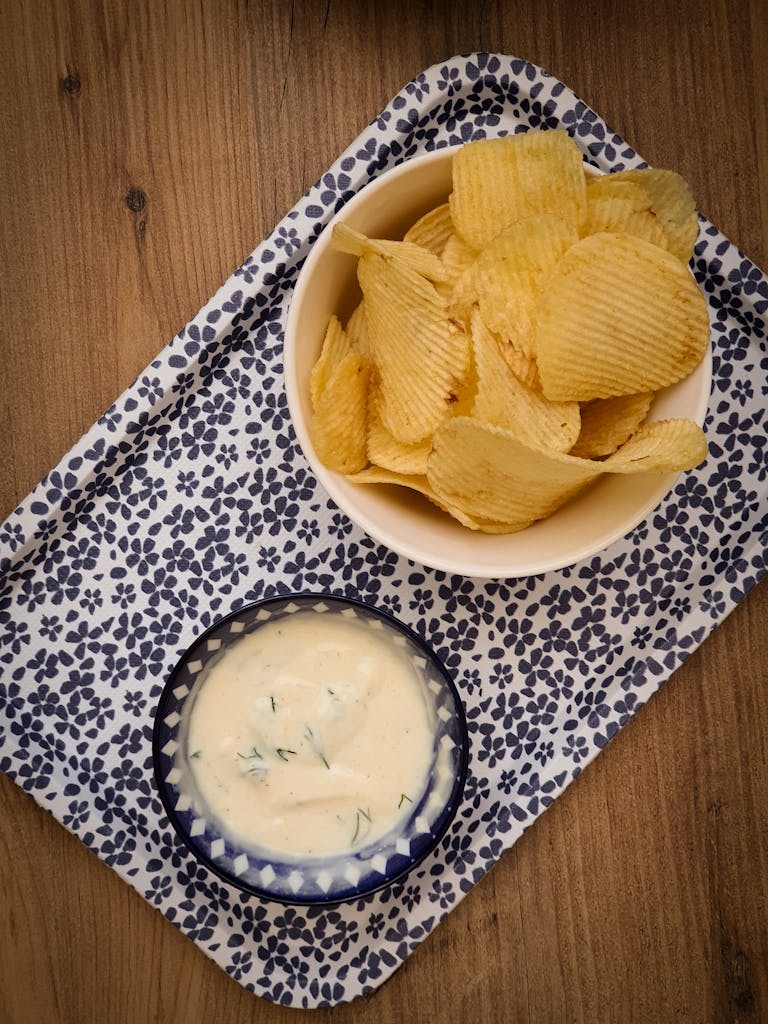 A delicious snack spread featuring potato chips and a creamy dip served on a patterned tray.