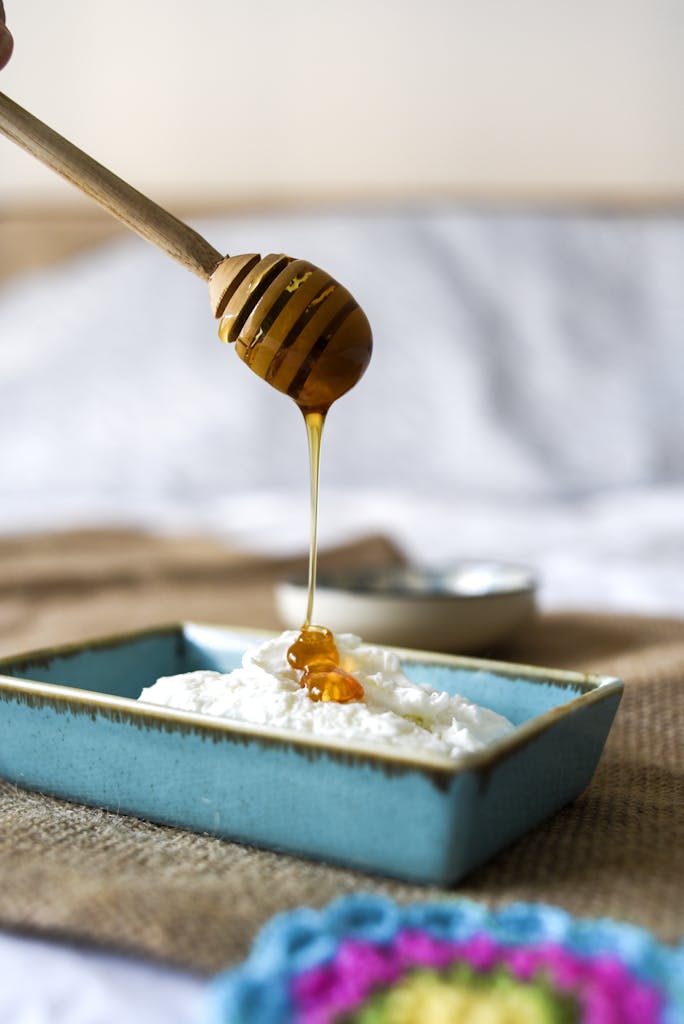 Close-up of honey drizzling over fresh ricotta in a blue dish. Perfect for food enthusiasts.