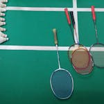Top view of badminton rackets and shuttlecocks on an indoor court.