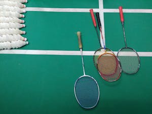 Top view of badminton rackets and shuttlecocks on an indoor court.